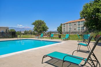A pool with a blue tinted water and a green bench